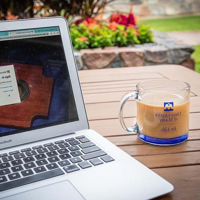 Glass coffee cup on an outdoor patio table near an open laptop